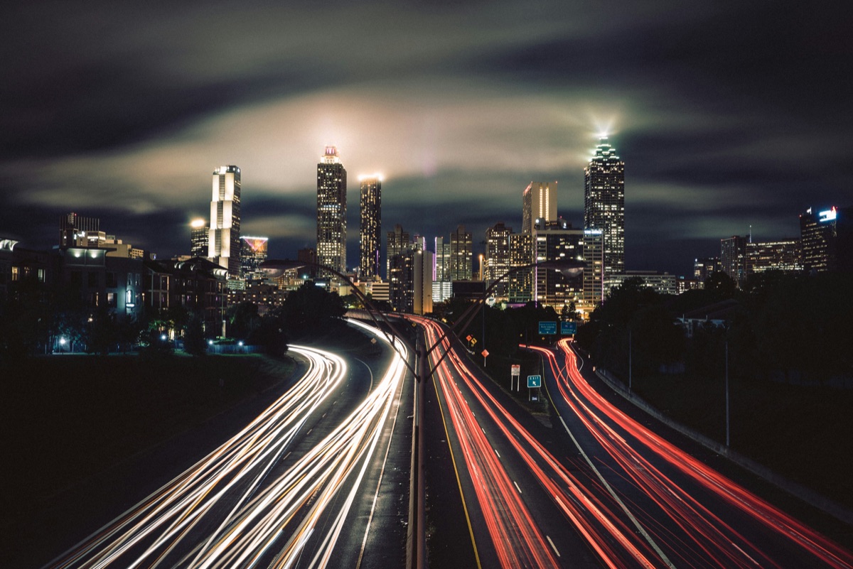 City skyline at night with light trails along the highway